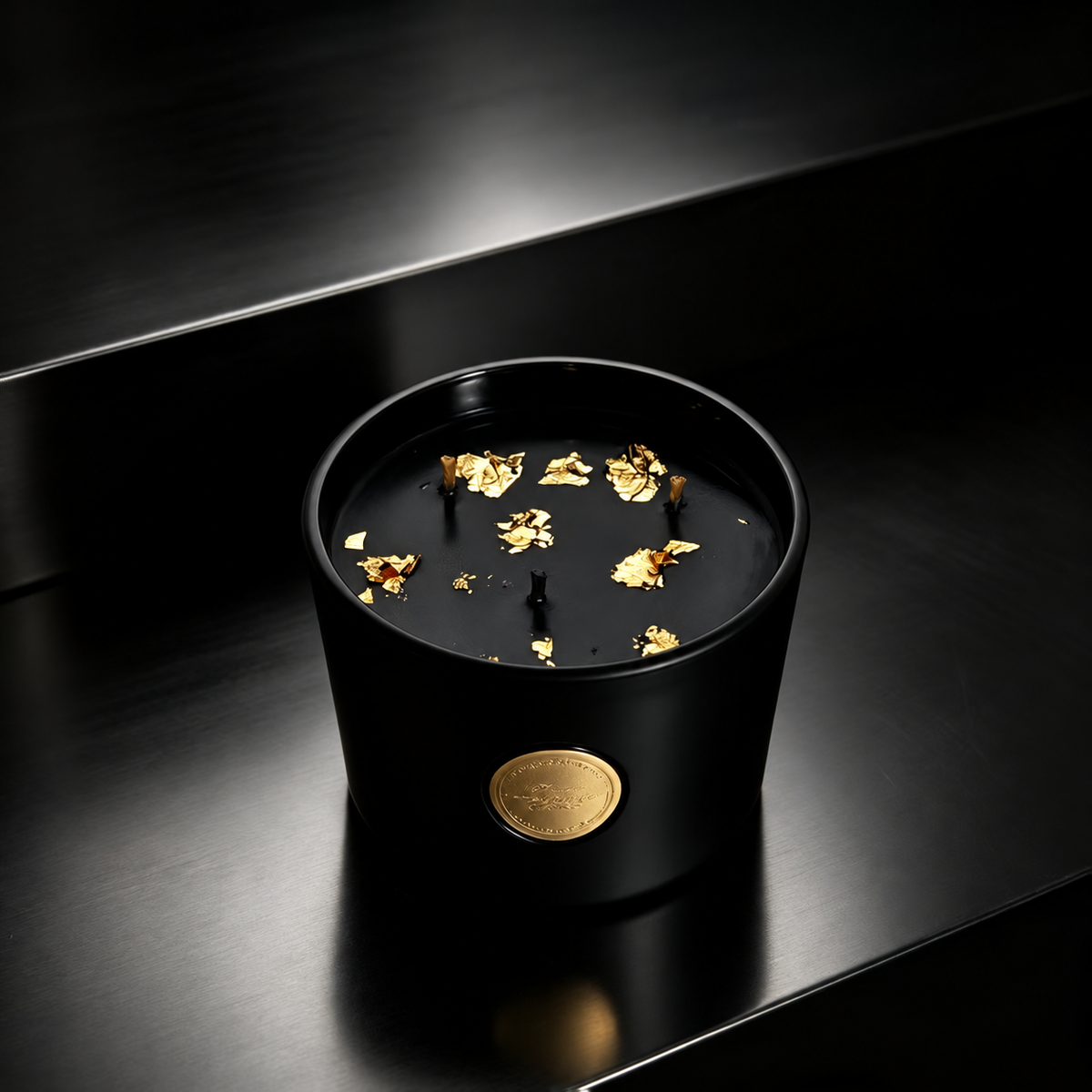 Black and gold three-wick soy candle in a matte black glass jar on a glossy black surface