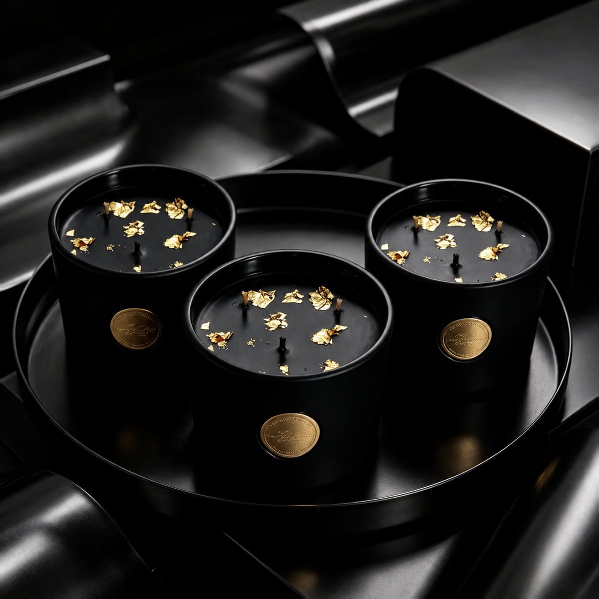 Three black and gold three-wick soy candles on a round black tray