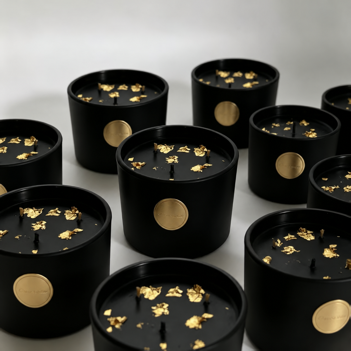 Group of black and gold three-wick soy candles with gold foil accents on white