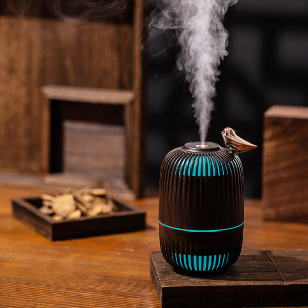 Dreambird Aroma Diffuser in Dark Walnut misting beside a tray of wood chips