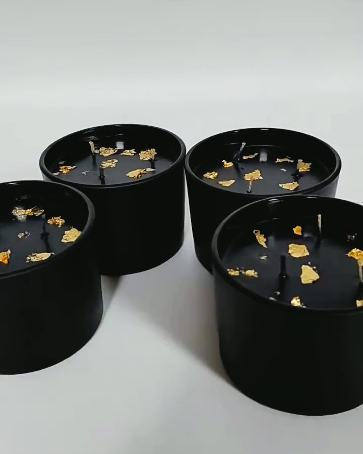 Close-up video of black and gold three-wick soy candles with gold foil on the wax