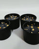 Close-up video of black and gold three-wick soy candles with gold foil on the wax